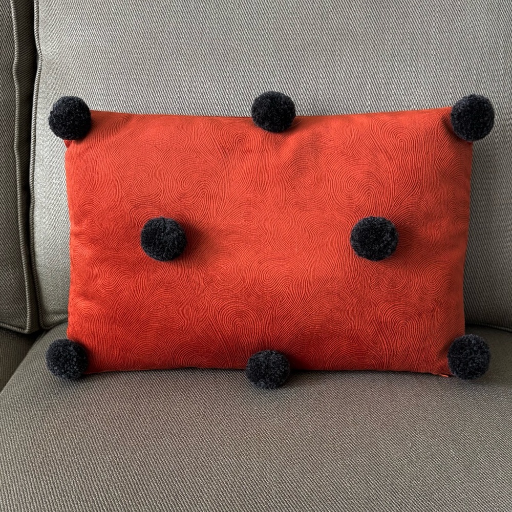 Orange Pillow with Black Pom Poms